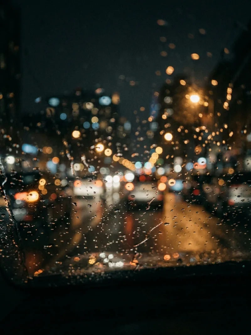 Blurred city lights through a windshield at night