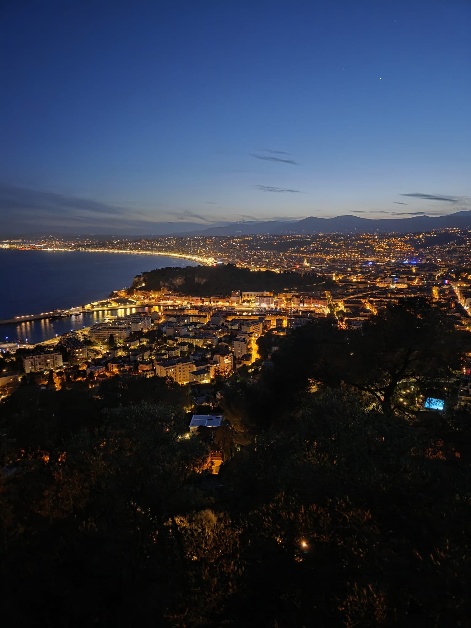 Nice at night viewed from the hills above — the Promenade des Anglais, Castle Hill and the city lights stretching along the bay